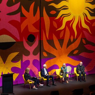 Four panel members on stage in front of colourful backdrop